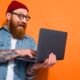Happy bearded social media marketer looking at laptop